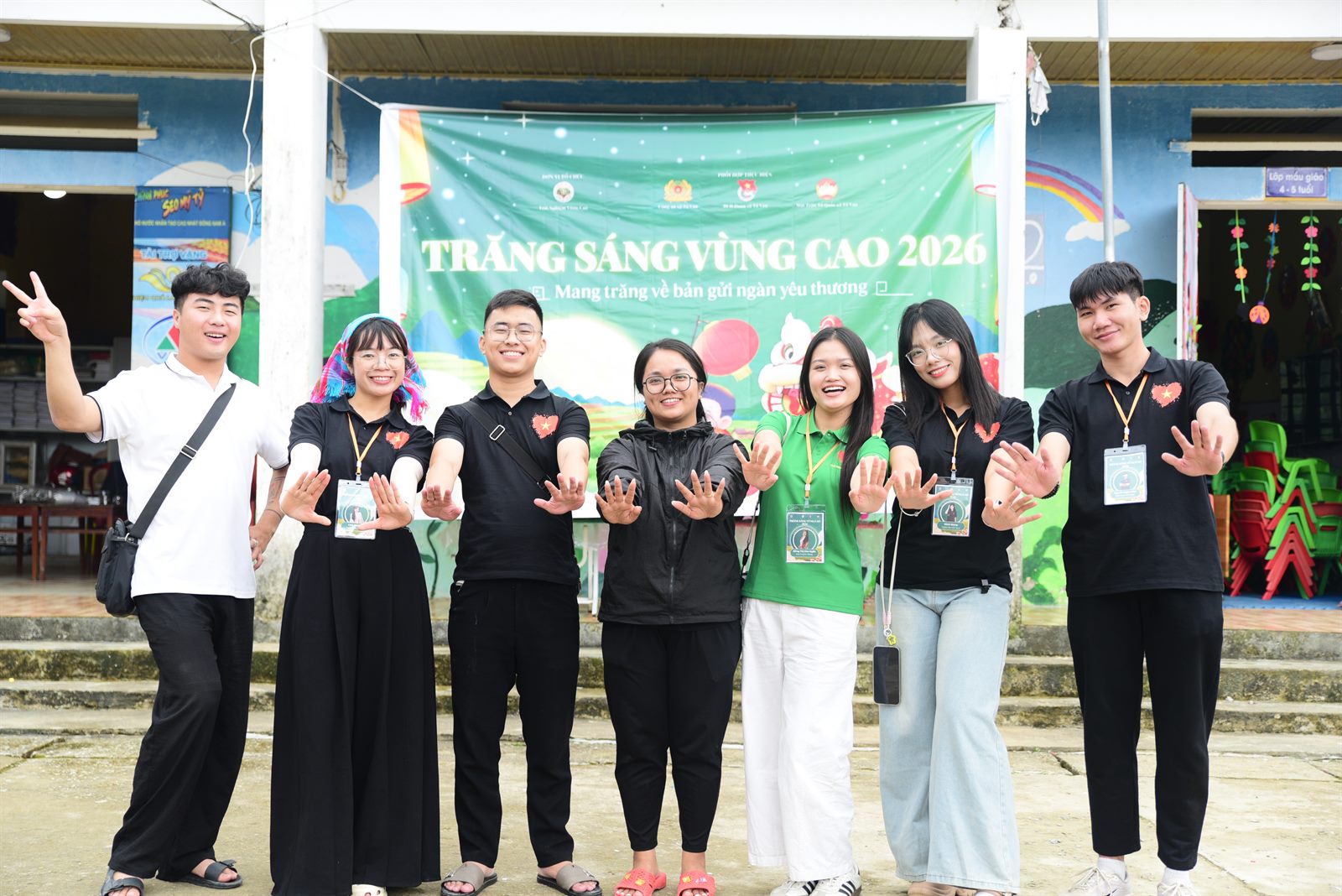 Các thành viên Trải Nghiệm Vùng Cao cùng giơ tay trước sân trường trong chương trình Trăng Sáng Vùng Cao 2026