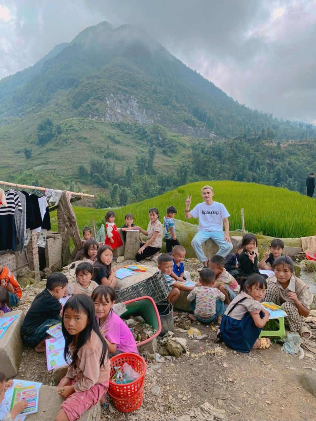 Các em nhỏ ngồi vẽ tranh dưới chân núi
