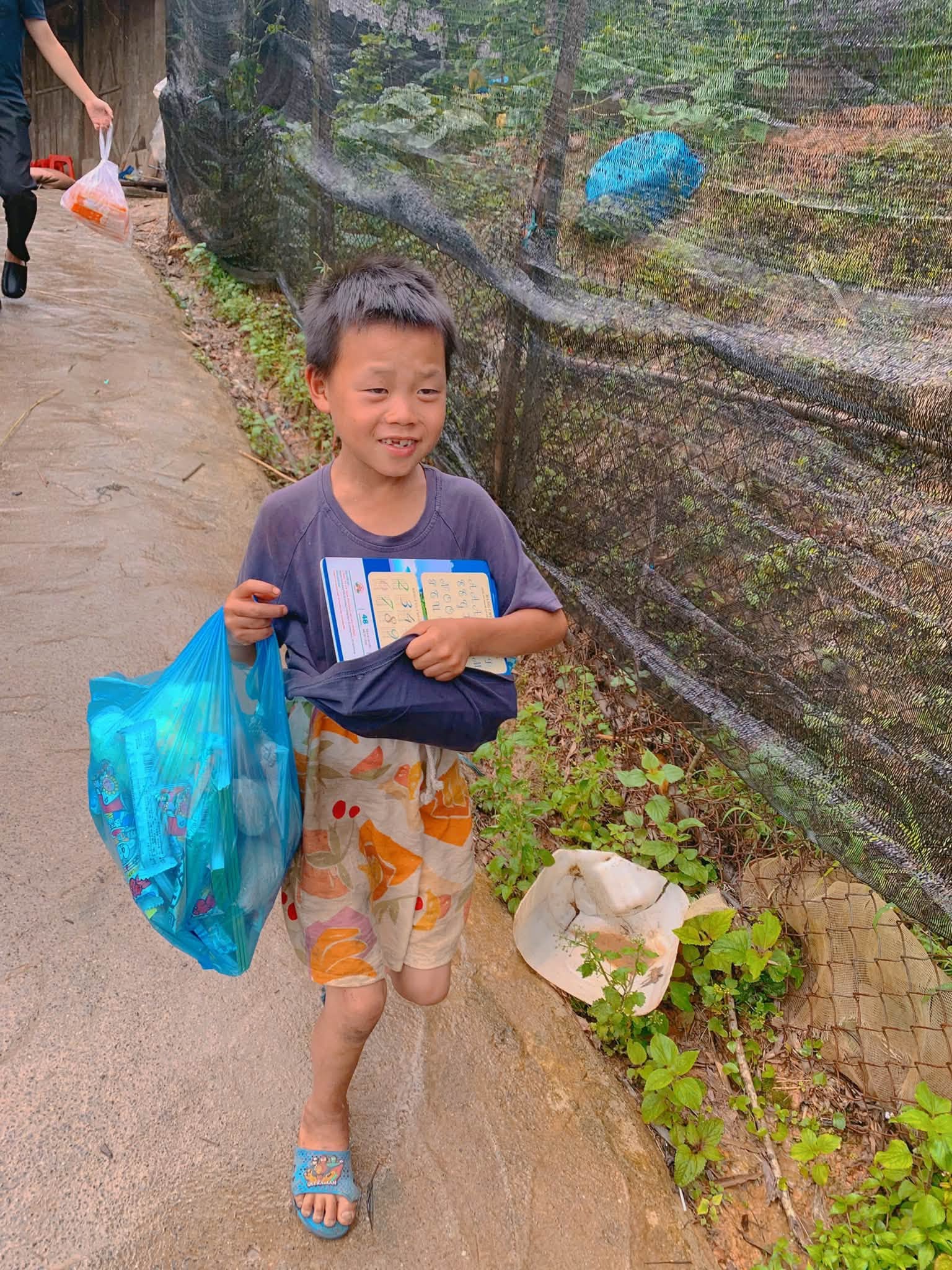 Em bé cầm quà trên con đường làng