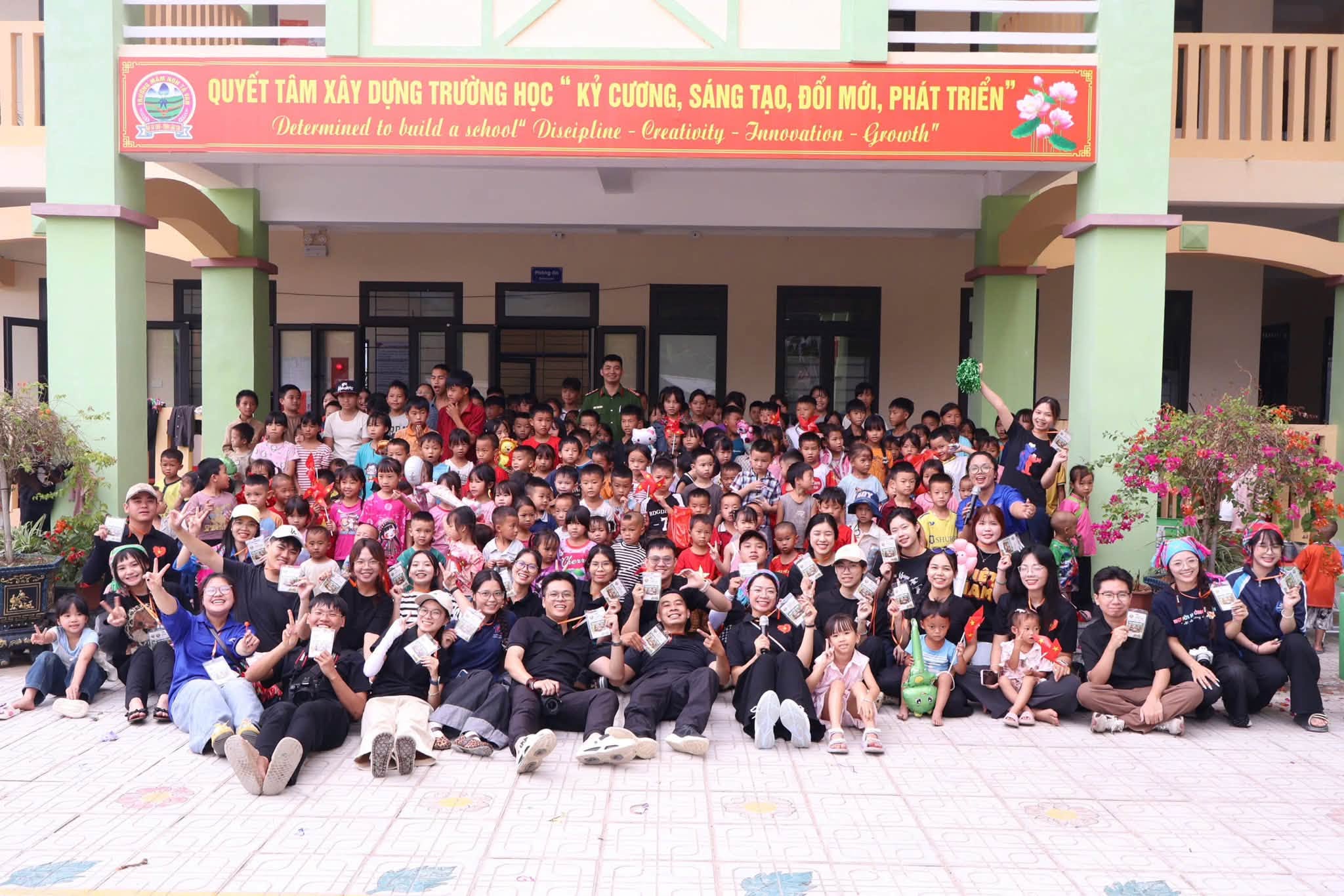 Tập thể tình nguyện viên chụp ảnh trước sân trường