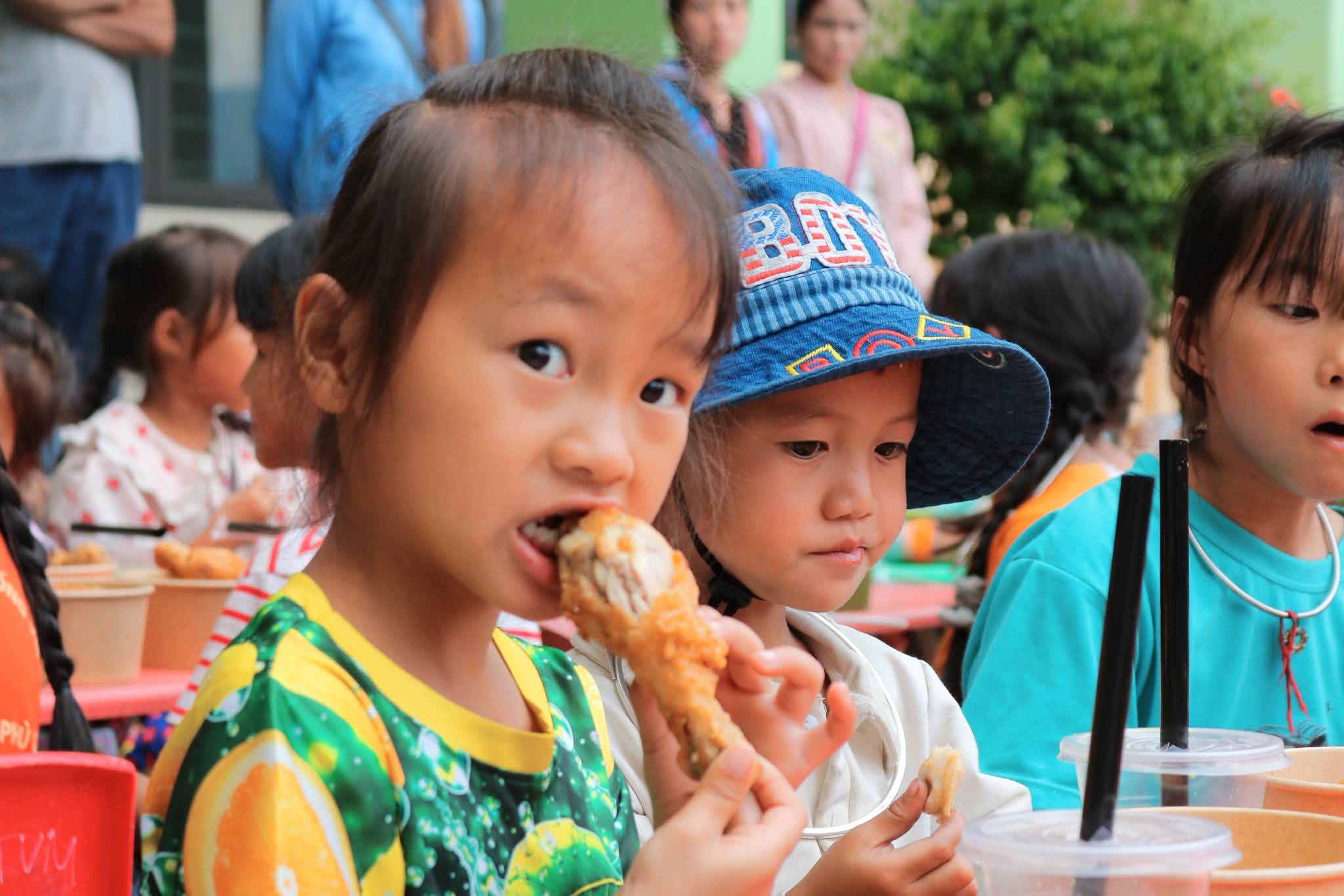 Em nhỏ ăn đùi gà bên các bạn trong bữa trưa
