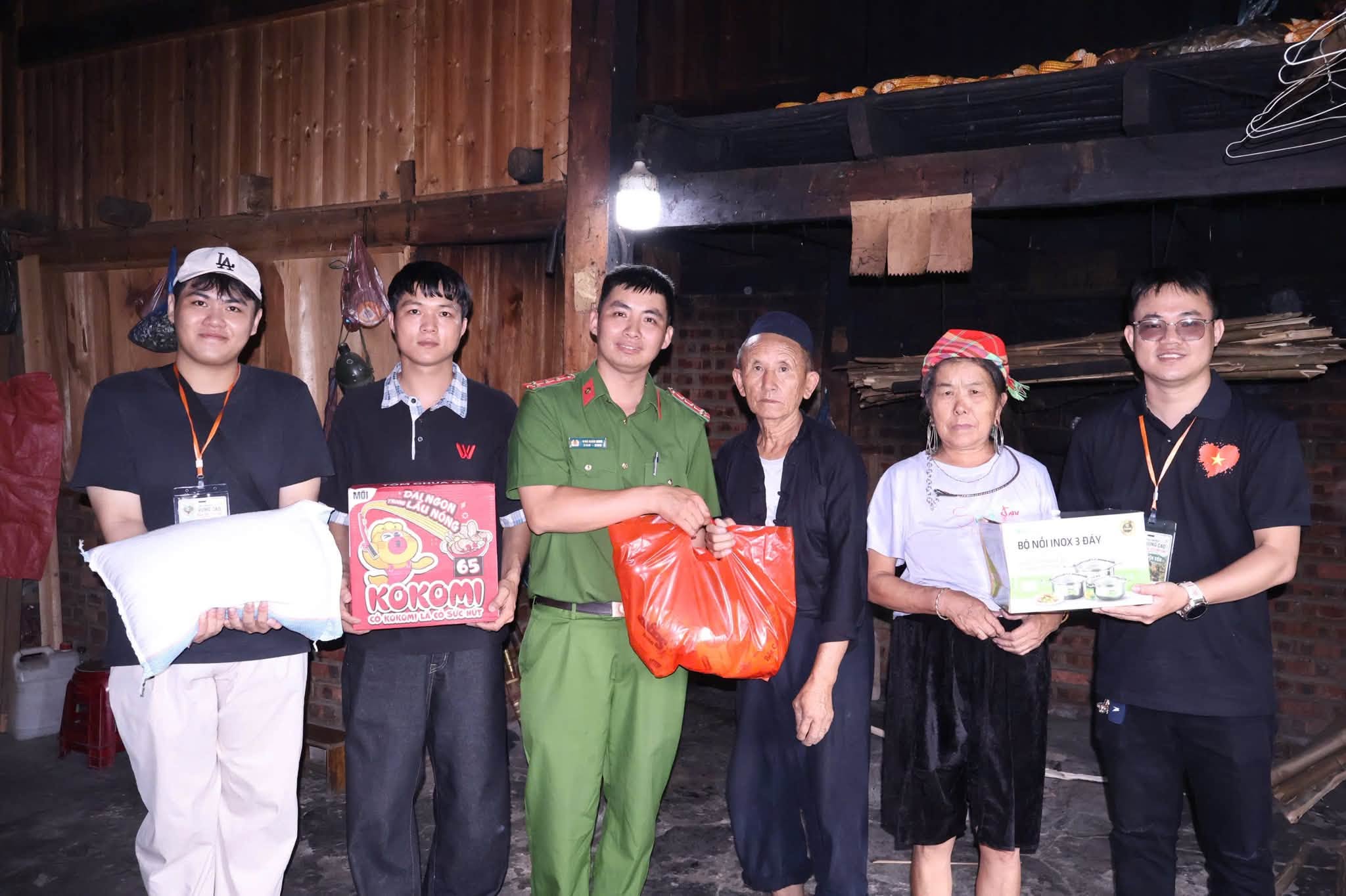 Đoàn tình nguyện cùng cán bộ địa phương trao quà cho hai cụ già trong căn nhà gỗ