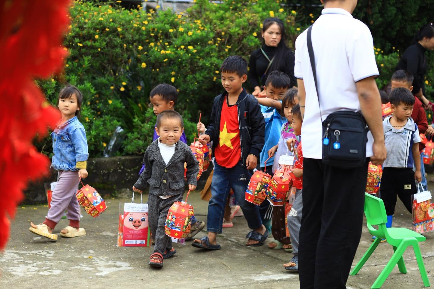 Các em nhỏ cầm đèn lồng đi trong sân trường