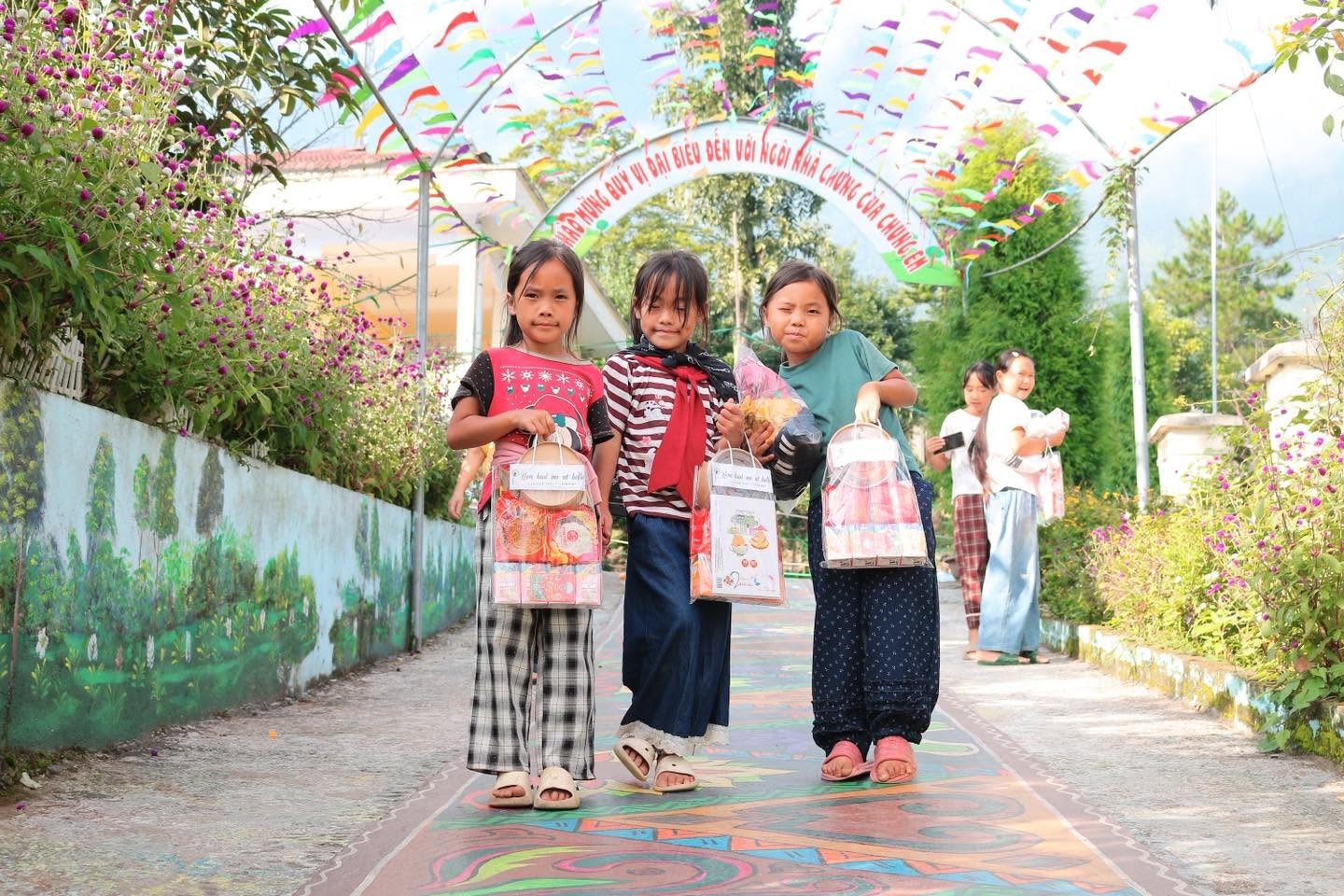Các em nhỏ cầm quà đứng trên lối vào điểm trường