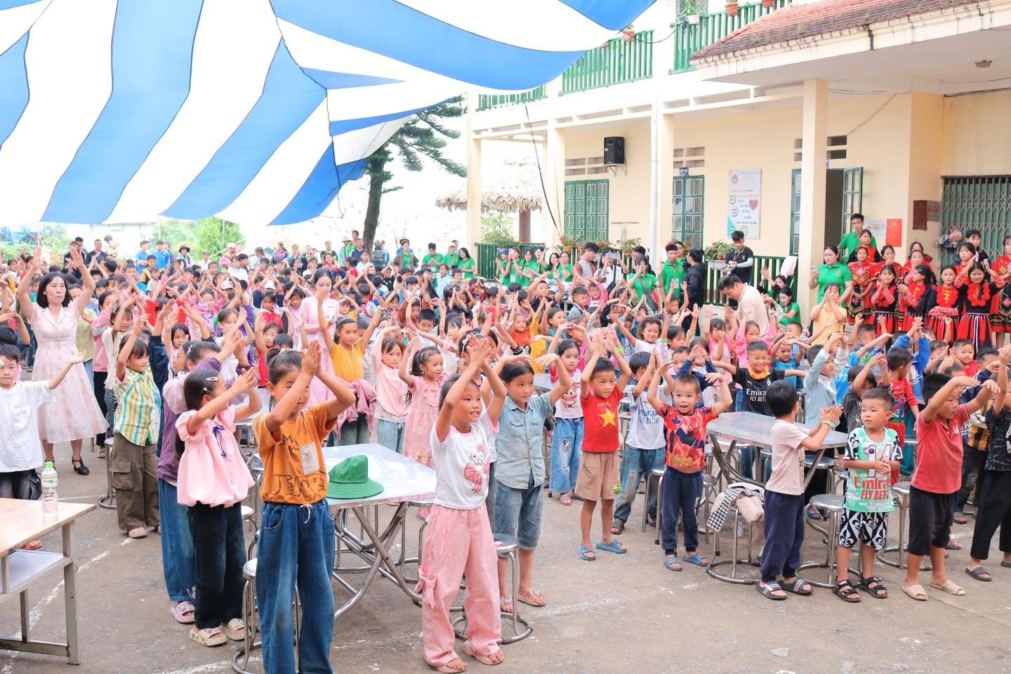 Các em nhỏ giơ tay reo hò giữa sân trường