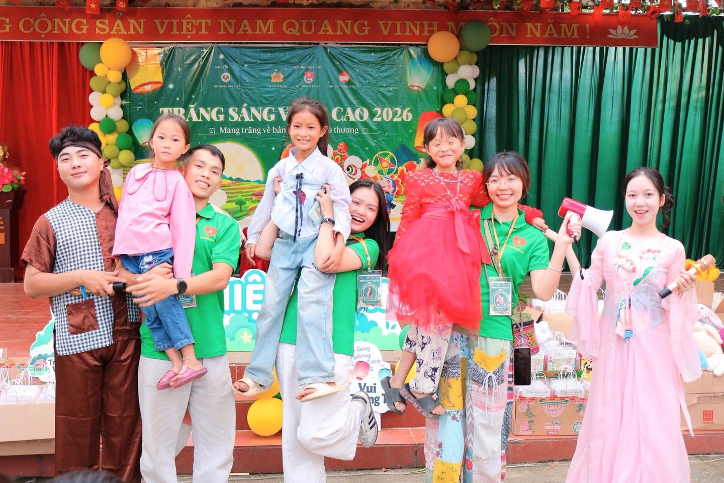 Tình nguyện viên cùng các em nhỏ chụp ảnh trên sân khấu