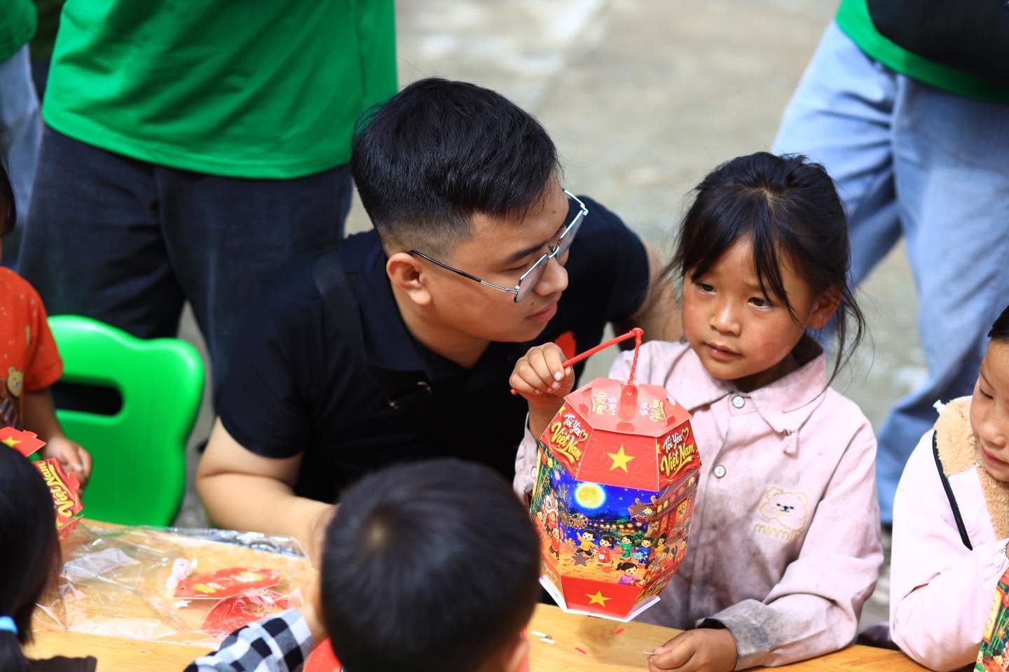Tình nguyện viên trò chuyện cùng một em nhỏ cầm đèn lồng
