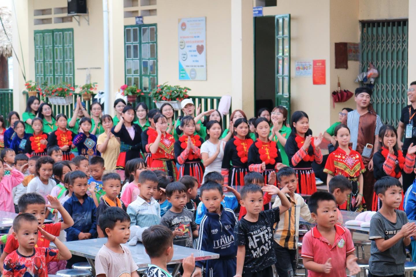 Các em nhỏ trong trang phục dân tộc ngồi xem chương trình